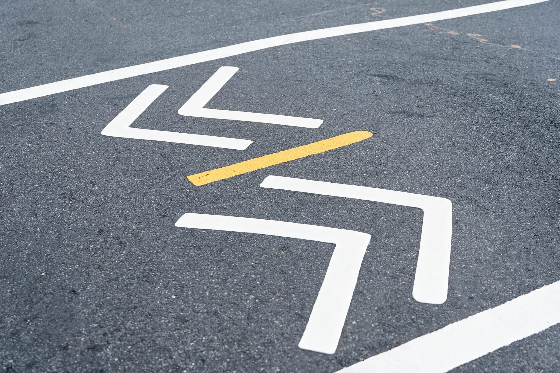 Chevrons blancs et ligne jaune peints sur l'asphalte